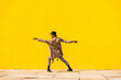 © VISTA by Westend61 - Young man dancing in front of yellow wall