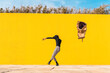© VISTA by Westend61 - Young man dancing in front of yellow wall