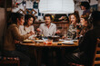 © qunica.com - A group of people gather around a table enjoying food and beverages, creating a warm and lively atmosphere indoors. The setting conveys companionship, laughter, and a sense of welcoming coziness.
