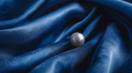 Wall Mural - a single white pearl resting on a blue patterned fabric.
