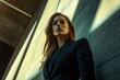 © Vibu design  gallery - A young woman in a dark suit stands against a textured wall, bathed in sunlight.