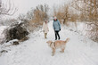 © StockMediaSeller - Two women walking a Golden Retriever in a snowy park, enjoying a winter day outdoors.