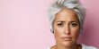 © imagineRbc - A woman with short gray hair wears headphones and displays a thoughtful expression. She stands out against a soft pink background, radiating concentration and engagement in her activity