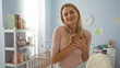 © Krakenimages.com - Woman smiling with hands on heart in cozy bedroom surrounded by soft toys and baby crib, expressing warmth and love.