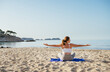 © Soloviova Liudmyla - Calm woman sitting and doing deep breathing and stratching exercises and meditating in early morning hours on sandy beach with calm sea waves. Mental health, people relaxing, traveling concept.