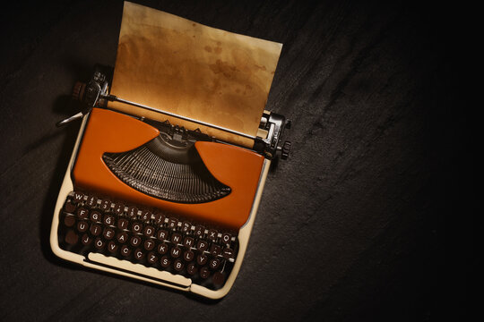 Old vintage typewriter with paper on black table, top view. Space for text
