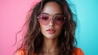 © Lazar - A striking portrait of a young woman with curly hair wearing round sunglasses against a vibrant pink and blue background, showcasing modern fashion and aesthetics.