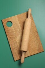 Wall Mural - Rolling pin and wooden board on green background, top view