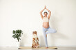© Pixel-Shot - Young happy sporty pregnant woman with cute Australian Shepherd dog meditating at home