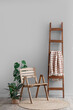 © Pixel-Shot - Chair, ladder with plaid and houseplants near grey wall in room