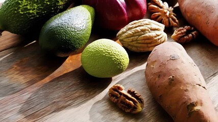 Poster - Sunlight illuminates fresh avocados, sweet potatoes, nuts, and onions arranged on a rustic wooden table, highlighting the vibrant colors and textures of these nutritious ingredients