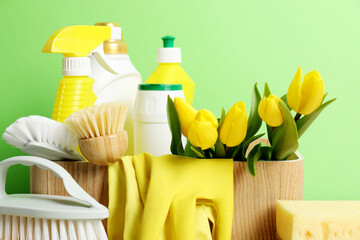 Wall Mural - Spring cleaning. Detergents, supplies and tulips on green background, closeup