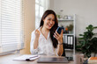 © David - Asian female worker holding mobile phone celebrating win receiving good news about job promotion, getting hired, feeling happy, rejoicing success with yes reaction working in office.