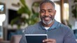 © artchvit - Retirement planning finance advisors guide. Smiling man using a tablet in a cozy indoor setting.
