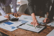 © crizzystudio - Businesswomen are pointing at financial charts and graphs while analyzing investment and financial performance, working together at office desk