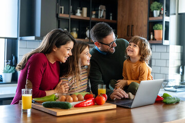 Wall Mural - Happy young family with kids in kitchen have fun using modern laptop together, enjoying weekend