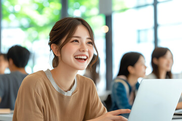 Poster - young woman smiles while working on laptop in bright, modern workspace. atmosphere is lively, with other people engaged in conversation in background