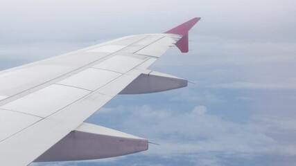 Wall Mural - view through plane window from inside airplane cabin while climbing flying over the sky with airplane wing winglet and fluffy cloud outside in summer daytime