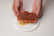 © ChristyMerry - Person sprinkles seasoning and marinating a piece of meat on a plate.
