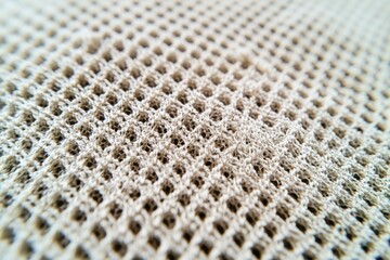 Poster - Extreme close-up of a textured beige mesh fabric showcasing the intricate pattern and unique surface, creating depth with subtle light and shadow play, and adding a tactile dimension.