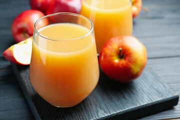 Wall Mural - Refreshing apple juice in glass and fruits on black wooden table, closeup