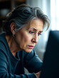 © Danielle - Senior woman staring sadly at her computer screen, feeling overwhelmed