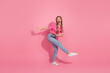 © deagreez - Young woman in striped t-shirt dancing joyfully on pink background