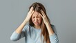 © Jiri - Woman Feels Desperate and Stressed Due to Severe Headache, Touching Her Temples While Standing Against a Gray Background