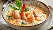 © Rachakrit - Golden coconut soup with shrimp in elegant bowl, garnished with fresh basil. delicious and vibrant dish
