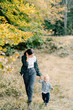 © VolodymyrNadtochii - Mom leads a little girl by the hand, straightening her hair, walking through the autumn forest