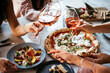 © FornStudio - Friends enjoy a dinner party with pizza and rose wine in a bar or a restaurant.