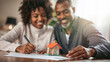 © Eduardo Accorinti - Mid adult black couple smiling and signing real estate contract for new home purchase with miniature house on the desk. African American man and woman buying new house to live together