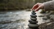 © Neo GT - A person carefully stacking smooth stones near a flowing river, symbolizing balance and mindfulness.
