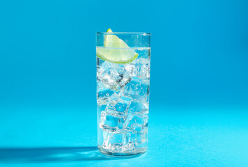 Wall Mural - Soda water with lime and ice cubes in glass on light blue background