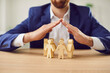 © Studio Romantic - Businessman covering wooden figures of people. Employer commitment to protecting the human rights, labor rights, and providing support and insurance to employees within the community.