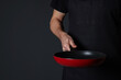 © New Africa - Chef holding frying pan on black background, closeup. Space for text