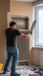 © NKTN - A worker applies plaster around a radiator in a room under renovation, with tools and materials scattered on the floor