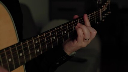 to play guitar a man plays the guitar in a dark room. close-up of a guitar neck