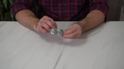 a man demonstrates a plastic orthosis for finger fixation during injury treatment. hands close-up.