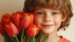 © PACHARA - A boy is holding a bouquet of red tulips