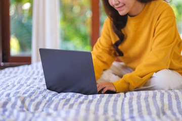 Wall Mural - closeup of a woman using and working on laptop computer while sitting on bed