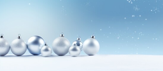 Poster - Blue and silver Christmas ornaments covered in snow arranged on a snowy surface with soft bokeh effect and empty space for text on top.