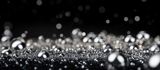 Poster - Glistening silver beads reflect light against a deep black background with varying sizes creating a shimmering contrast and a sense of depth