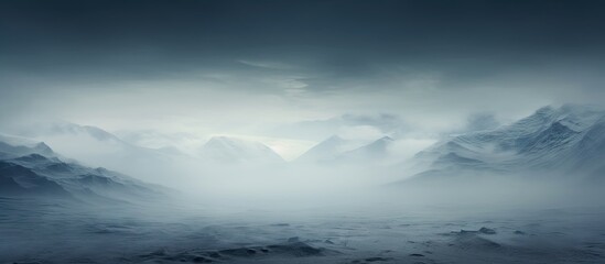 Fototapete - Misty landscape with dense fog covering dark mountains in the background, showcasing a moody atmosphere with muted gray and blue tones.