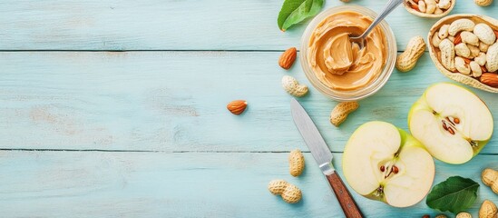 Poster - Fresh apple slices with creamy peanut butter and assorted nuts on light blue wooden table flat lay with knife and space for text on the left
