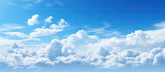 Poster - Serene blue sky with soft white fluffy clouds creating a tranquil scene ideal for copy space positioned in the upper half of the image
