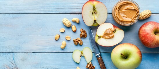 Poster - Fresh apple slices with creamy peanut butter in a clear bowl on a light blue wooden table featuring scattered nuts and a knife.