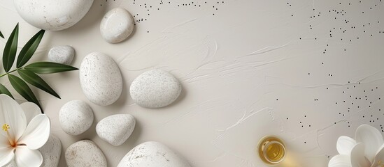 Poster - Flat lay image featuring white spa stones and green leaves on a light beige background with aromatic oils in a cup creating a calming ambiance.