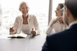 © fizkes - Laughter in professional communication. Joyful senior female team leader ceo employee express funny idea on staff meeting at boardroom feel happy of business success having fun moment at conversation