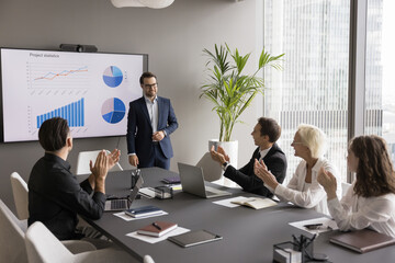 Fototapete - Recognition of achievement. Smiling businesspeople group office workers colleagues meet at boardroom table clap hands applause project manager celebrate success after presentation of statistic results